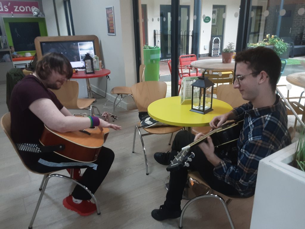 Musician David playing guitar with Alan, a resident at Woodside Care Village